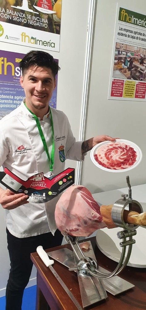 El influencer rural, Joaquín López 'Bernabé' cortando jamón en el stand de FHALMERÍA